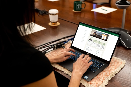 An over-the-shoulder view shows a person typing on a laptop at a conference table, with the myJPIA 2.0 website visible on the screen.